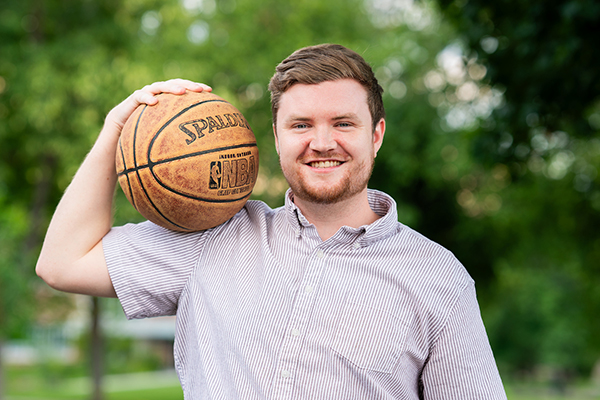 Sam Jones holds a basketball and smiles