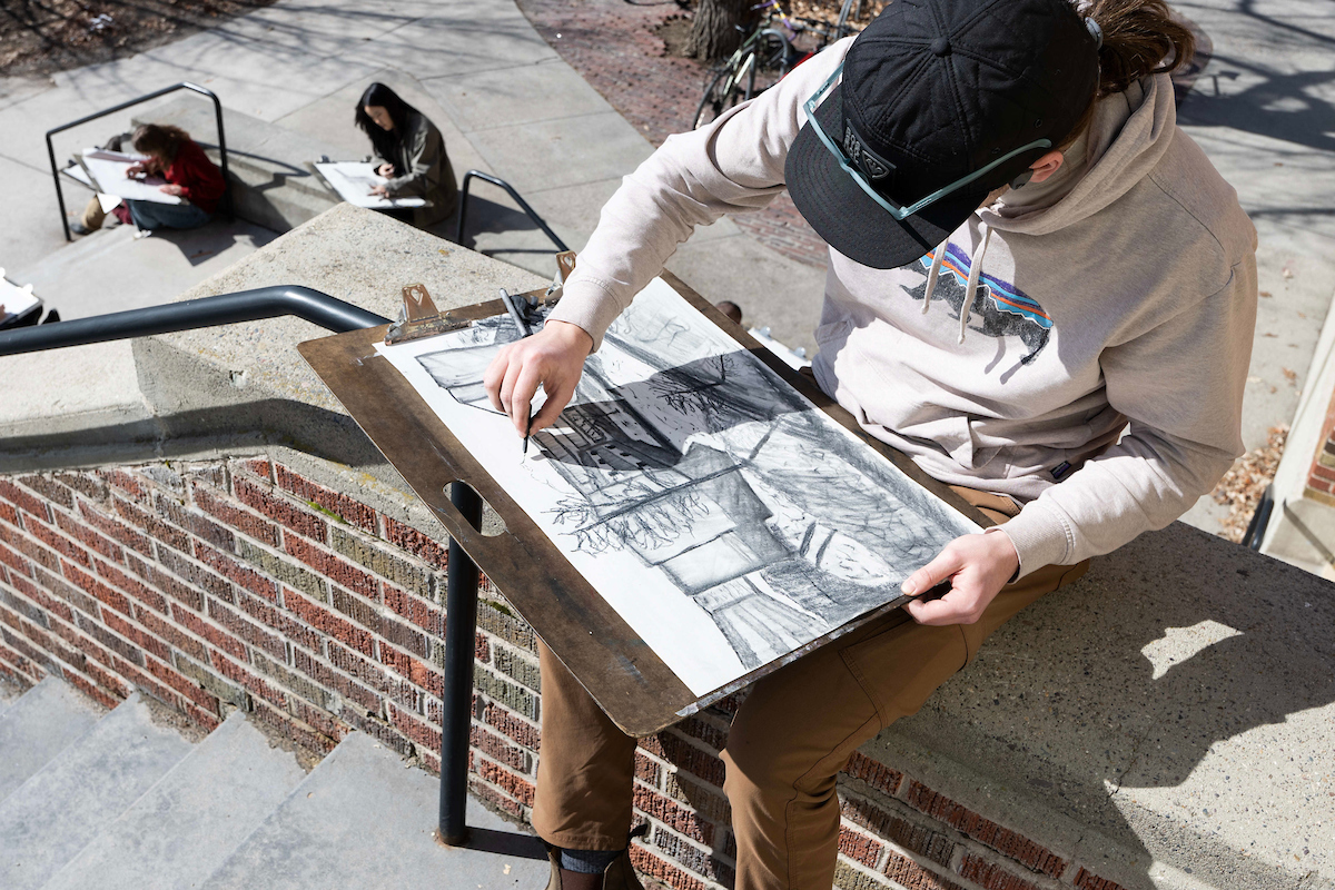 An art student draws while sitting outside